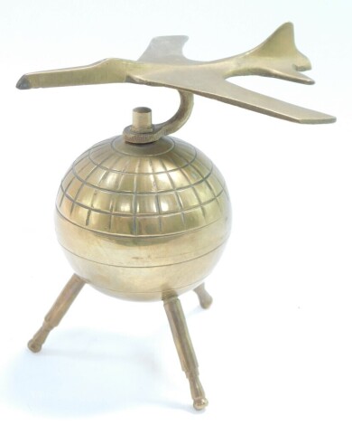 An atomic brass desk stand, modeled as an aeroplane atop a globe, 12.5cm wide.