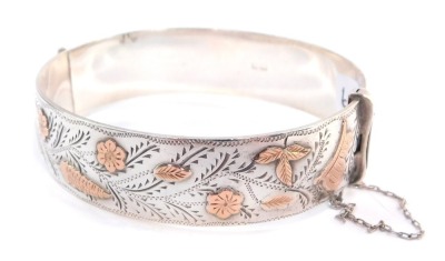 A silver and rose gold plated bangle, engraved and embossed with a bird, butterfly, flowers and leaves, on a snap clasp, with safety chain as fitted, 1.7oz.