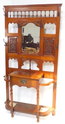 A Victorian walnut hall stand, with a central cartouche shaped mirror, with bevelled plate, surrounded by foliate carved panels, cast hooks, etc., the base with a frieze drawer, flanked by recesses for umbrellas, each with a metal liner, 106cm wide.