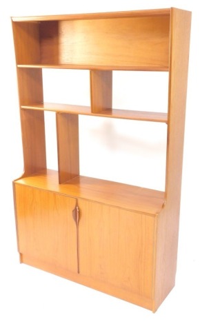 A 1970's teak unit, with an arrangement of shelves, above two doors, each with a piano hinge on a plinth, lacking sliding doors, 168cm high, 107cm wide.