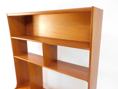 A 1970's teak unit, with an arrangement of shelves, above two doors, each with a piano hinge on a plinth, lacking sliding doors, 168cm high, 107cm wide. - 2