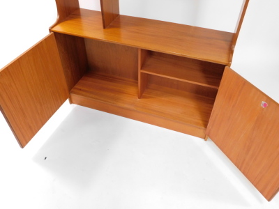 A 1970's teak unit, with an arrangement of shelves, above two doors, each with a piano hinge on a plinth, lacking sliding doors, 168cm high, 107cm wide. - 3