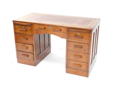 An Art Deco desk, the rectangular top with a red leather inset bordered with Greek key design in gilt, above an arrangement of nine drawers and two sliding sections, each with rectangular solid handles, on a plinth, 73cm high, 122cm wide, 69.5cm deep.