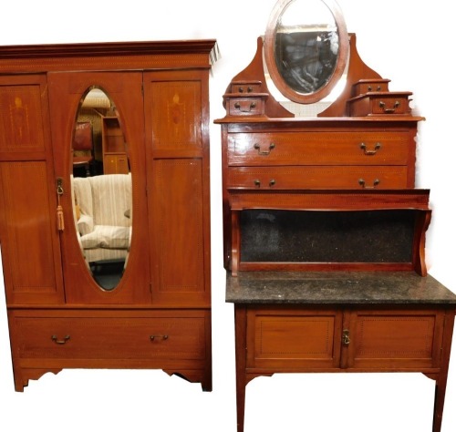 An Edwardian mahogany three piece bedroom suite, comprising wardrobe with oval bevelled mirror plate and a drawer, 130cm wide, a dressing table with oval bevelled plate, four trinket drawers and two long drawers, on brass castors, 101cm wide, and a washst