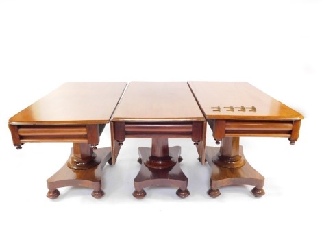 An early Victorian mahogany triple pedestal dining table, comprising a drop flap centre table and two D end tables, each raised on a hexagonal and turned column over a quatrefoil base, raised on bun feet, 76cm wide, 180cm wide, 237cm extended, 123cm deep.