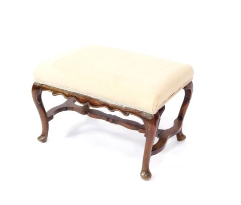 A Georgian style mahogany stool, upholstered in overstuffed cream draylon, raised on cabriole legs, united by a shaped stretcher, 61cm wide.