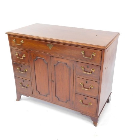 A Georgian mahogany side cabinet, with a three division long drawer, over a pair of cupboard doors, opening to reveal a single shelf, flanked by six drawers, raised on out swept feet, 86cm high, 107cm wide, 52.5cm deep.