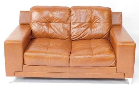 A tan leather two seater sofa, raised on metal bracket feet, 162cm long.