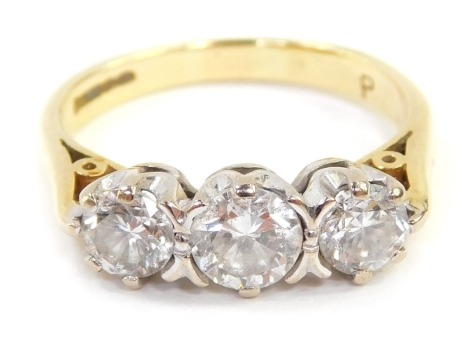 An 18ct gold three stone diamond ring, the central round brilliant cut stone in four claw setting, 4.4mm x 2.8mm, approximately 0.35ct, flanked by two smaller stones, 4mm x 2.4mm, approximately 0.21ct's each, in a platinum claw setting with pierced design