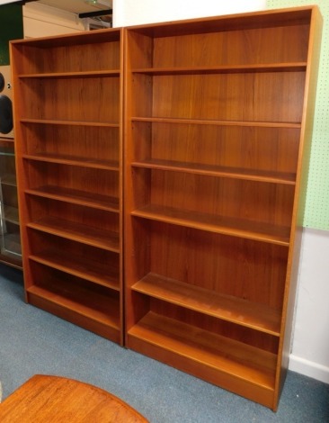 A pair of 1970s teak open bookcases, each with adjustable shelves, on a plinth, 187cm high, 91cm wide.