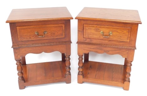 A pair of oak side cabinets, each with a rectangular top and a moulded edge, above a frieze drawer, on turned legs, under tier, 82cm high, 63cm wide, 46cm deep.