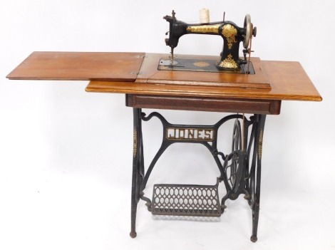 A Jones treadle sewing machine, in an oak and cast iron table base, with end supports, 93cm wide.