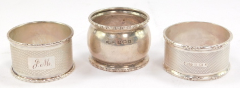 Two silver napkin rings, with engine turned decoration, and rectangular reserves, one monogram engraved, Birmingham 1955 and 1954, and a George VI silver napkin ring, monogram engraved, Birmingham 1945, 2.0oz. (3)