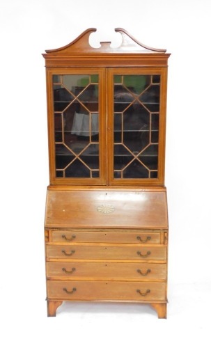 An Edwardian mahogany and satinwood banded bureau bookcase, the break arch pediment over a pair of glazed doors enclosing three shelves, above a fall flap with paterae inlay opening to reveal two drawers and eight recesses, over four long graduated drawer