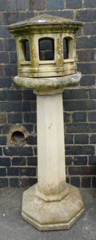 A reconstituted stone bird table, with folly shaped top and large column on octagonal base, 124cm high, 44cm wide.