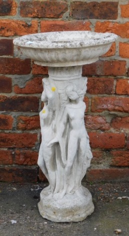 A reconstituted stone bird table, the circular top supported by three neo-classical female nude figures, on a shaped base, 76cm high, 41cm wide.