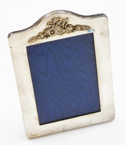 An Elizabeth II silver photograph frame, of rectangular design with arched top and applied floral basket detailing, makers stamp GK and CK, on blue velvet back, London 1986, 19cm x 13cm.