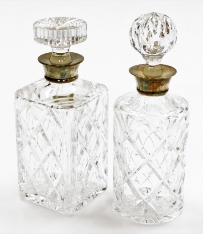 A pair of cut glass decanters, each with silver collar, one square set, Birmingham 1974, 25cm high, and a circular example with silver collar to the same date, 27cm high. (2)