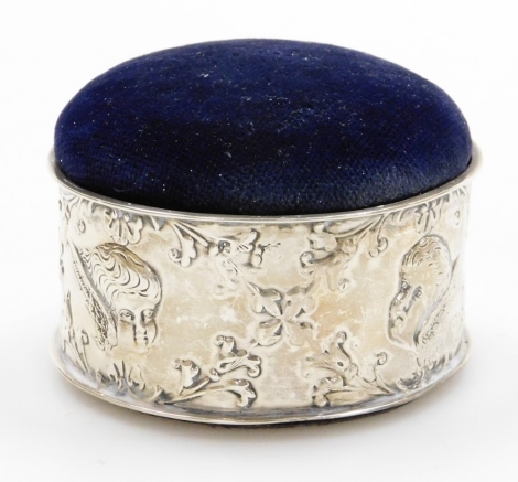 An Edward VII circular silver trinket box, the silver collar with cherub and cross flower detailing, maker RDC, Chester 1905, with a blue velvet lift up pin cushion top, 5cm high, 8cm diameter.