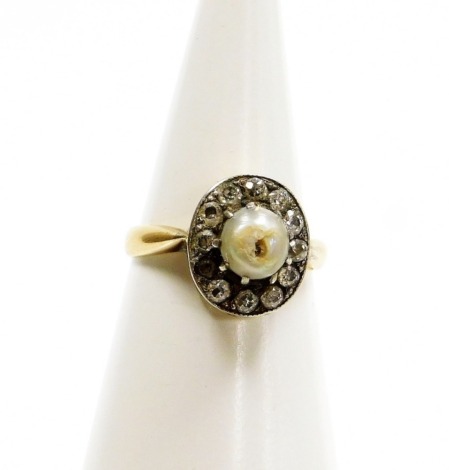 A dress ring, with borders of tiny diamonds and a central pearl, in a platinum setting on a yellow metal band, unmarked, ring size K, 3.3g all in.