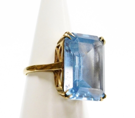 A dress ring, set with large rectangular aquamarine stone, in four two point claw setting, on a raised basket with pierced shoulders, yellow metal stamped 9ct, ring size P, 8g all in.