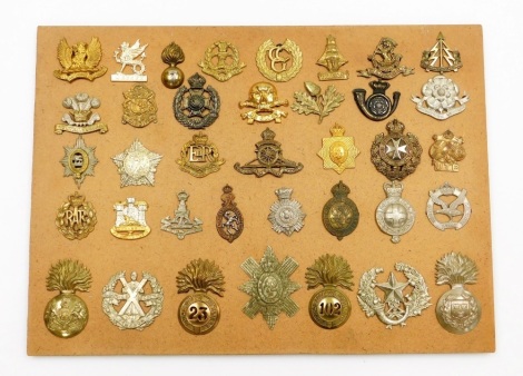 A collection of military cap badges, including reproductions, Glider Pilot Regt, Royal Madras Fusiliers Military Police, Wessex Regt, etc., on panel (37).