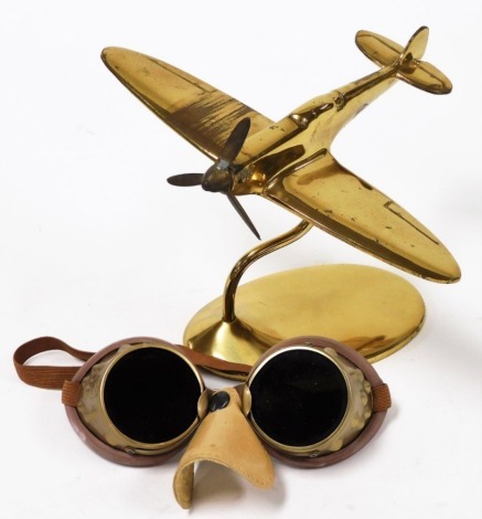 Aviation Interest. A brass model of a Spitfire, on stand, 14cm high, and a pair of aviation goggles. (2)