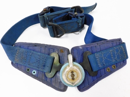 An airman's parachute release belt, with central release on blue material straps.