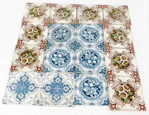 A group of Edwardian wall tiles, to include a set of nine tiles with brown mottled detailing of daisies, 15.5cm x 15.5cm, and seven blue and white floral tiles. (a quantity)