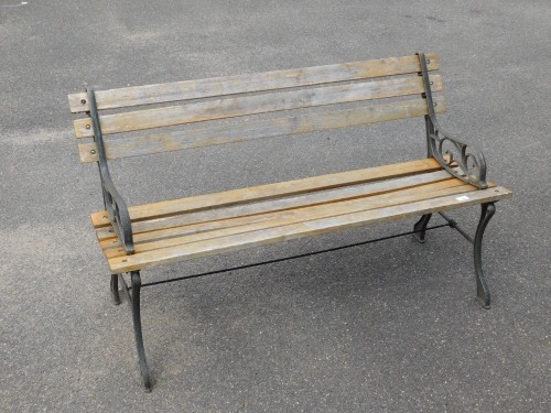 A slatted garden bench, with metal scroll support ends, previously stained, 74cm high, 120cm wide, 45cm deep.