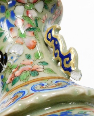 A 19thC Chinese Canton porcelain baluster vase, decorated with panels of ladies at leisure, the everted neck with ear handles, the background with flowers, ruyi fungus and butterflies on a celadon ground, 23cm high. (AF) - 21