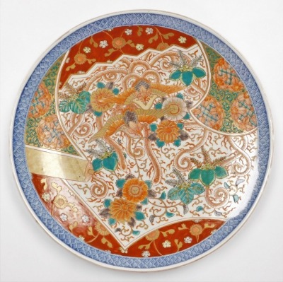 A Japanese Imari charger, decorated with a central design of phoenic and chrysanthemums within a shaped panel, underglaze blue diaper border, the reverse with tasselled cash in blue, Meiji period, 46cm diameter.