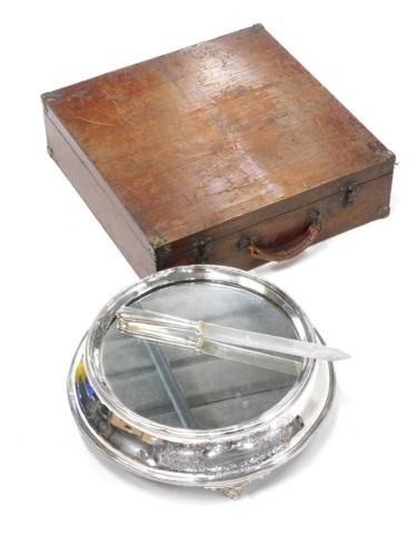 A silver plated wedding cake stand, with mirrored top, the base engraved with flowers, etc., on tapering feet, (AF) and a cake knife, 39cm wide, in a fitted case.