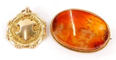 Two items of jewellery, to include a 9ct gold circular shield fob, bearing inscription Combined Average, Jersey and Rennes Races T. Unwin, 4.6g, and an oval agate brooch in a yellow metal frame, unmarked, 4cm wide. (2)