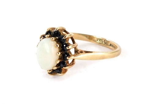 A 9ct gold dress ring, the central cluster with oval opal surrounded by dark blue round brilliant cut stones, in a raised basket setting, ring size N½, 2,5g all in. (boxed)