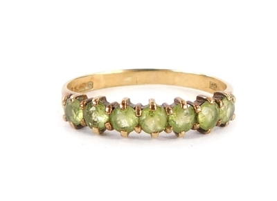 A 9ct gold half hoop eternity ring, set with seven pale green stones, with two splayed shoulders, ring size O, 1.4g all in. (boxed)