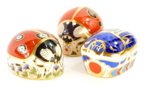 Three Royal Crown Derby porcelain paperweights, a Millennium bug, with gold coloured stopper, and two ladybirds, one with a gold coloured stopper, the other with a silver coloured stopper, boxed. (3)