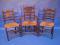 Three carved oak kitchen chairs with ladder backs and rushed seats