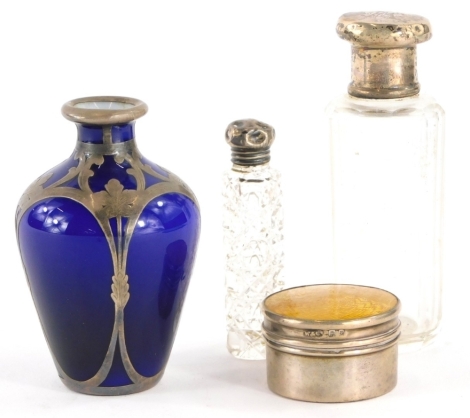 A collection of small silver, to include a silver dressing table pot, the lid decorated with yellow enamel, two silver topped scent bottles, and a miniature blue vase with sterling silver floral decoration, 9cm high. (4)