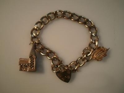 A 9ct gold flat curb charm bracelet with two charms and padlock clasp