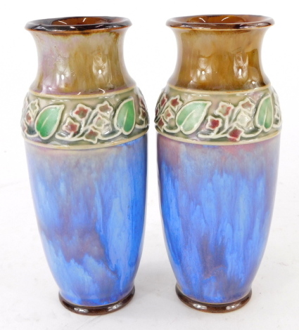 A Royal Doulton stoneware vase, decorated with a band of leaves, etc., with purple, turquoise and green ladies, etc., impress mark to underside, 16cm high.