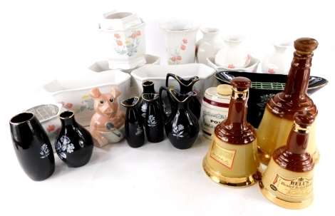 A large quantity of Wade vases and other items, to include a Ringtons 1988 pieces, graduated set of Bells Whisky decanters (lacking contents), Wade Black Lace vases, money box, etc.