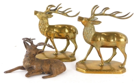 A pair of brass models of stags, each on a canted rectangular base, and a cold painted spelter figure of a recumbent stag. (3)