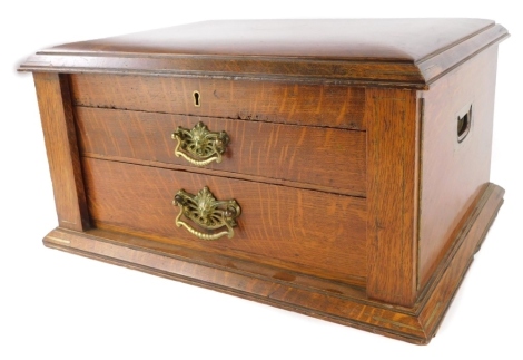 An early 20thC oak cutlery canteen, the hinged lid inset with a brass shield shaped cartouche above two drawers, 47cm wide.