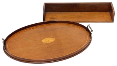 An early 20thC mahogany and boxwood strung oval tray, with brass handles, 52cm wide, and a 19thC portable book rack, 56cm wide.