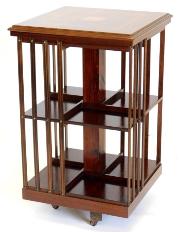 A mahogany revolving bookcase, the square top inlaid with a central patera within a satin wood crossbanded border, above slatted divisions for books, on an egg shaped base, 79cm high, 48cm wide.