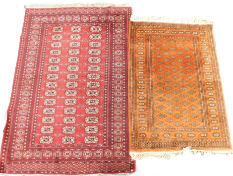 Two Afghan Belouch rugs, each with a design of medallions on a red ground.