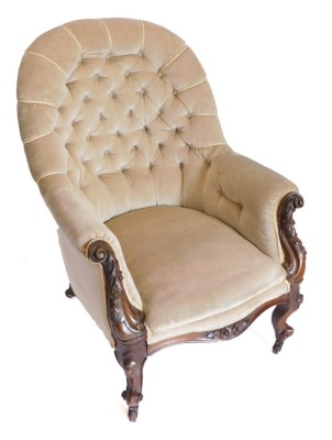 A Victorian walnut armchair, with beige buttoned back, with scroll carved supports on shaped legs with castors.