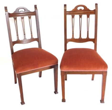 A pair of Edwardian mahogany side chairs, each with a pierced rail back, a padded seat on square tapering legs.