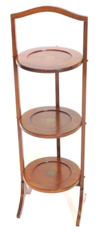 An Edwardian mahogany and boxwood strung three tier cake stand, with transfer printed simulated inlay, 85cm high.